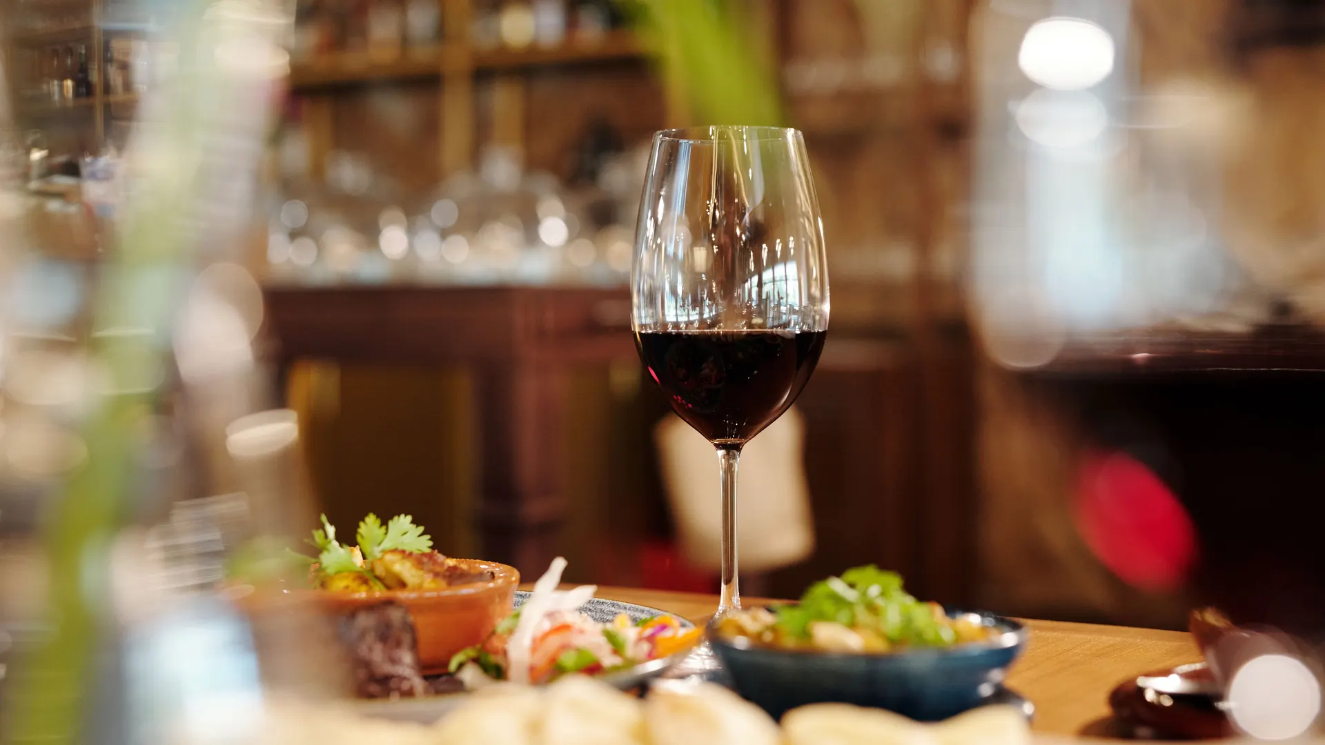 Glass of red wine on a restaurant table with sharing dishes